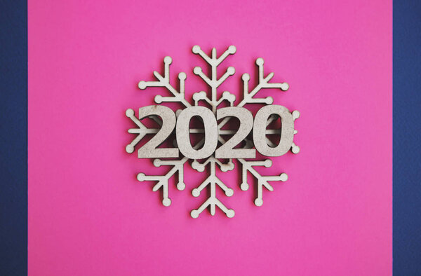 2020 winter holidays flat lay background.Pink color backdrop with wooden snowflakes in flat layout.Handmade rustic wood crafts and figures for Happy New Year wallpaper design