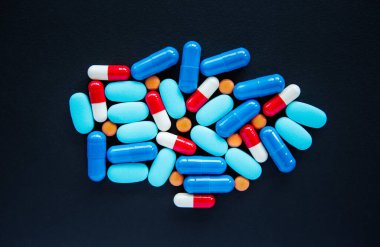 Düz zeminde çok renkli tıbbi haplar siyah zeminde yatıyordu. Düzlükte hastalık tedavisi için kimyasal ilaçlar. Sağlıklı yaşam için ilaç. Hastalıkları tedavi etmek için renkli kapsüller.