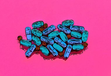 Düz zeminde bulunan tıbbi haplar pembe arka planda yatıyor.Güçlü sağlık için vitamin ve kimyasal ilaçların gösterimi. Hastalık tedavisi ve sağlıklı yaşam için ilaçlar. Çok renkli ilaç kapsülleri
