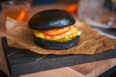 Amerikan fast food restoranında büyük siyah hamburger. Lezzetli hamburger menüleri götürüyor. Yakından lezzetli ve sağlıksız fast food. Yanmış peynirli ve sebzeli ızgara çizburgerin tadını çıkarın.