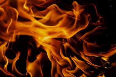 Güzel şömine, yakın mesafede yanıyor. Canlı turuncu ve kırmızı alevler karanlıkta yanıyor.