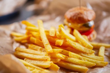 Fast food teslimatı. Patates kızartması ve hamburger hazır, kahverengi kağıtta servis ediliyor. Lezzetli fast food paket servis menüsü..
