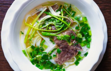 Vietnam restoranında beyaz kasede Pho bo çorbası. Baharatlı ve doğal malzemeli Asya mutfağı. Erişte, sığır eti, yeşil soğan ve baharatlı çorba.