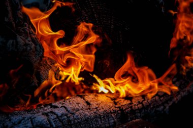 Şömine geceleri odun yakar. Yakından ateş alevler saçar.