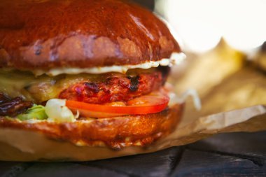 Fast food menülerini çıkar. Kahverengi kağıtla servis edilen hamburger servisi. Et eti, sos ve taze sebzeli lezzetli hamburger.