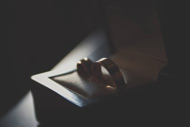 Açık kutuda altın alyans. Gelin ve damat için bir çift güzel nişan mücevheri. Karanlık odada küçük hediye paketi. Evlilik teklifi için lüks mücevherler.