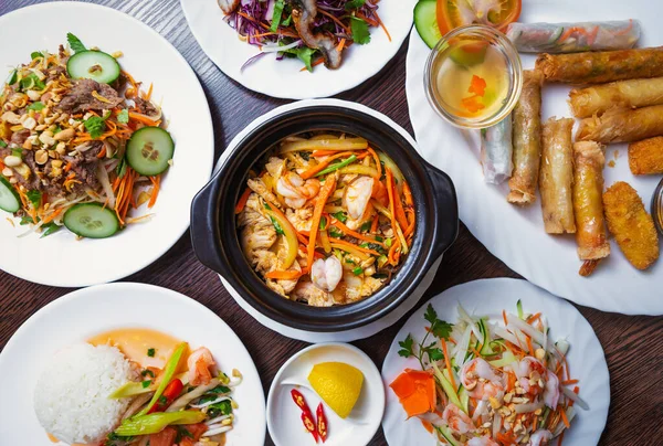 Asian dinner served in restaurant.Delicious Vietnamese sea food in top view.Jambalaya with shrimps,spring rolls and salads served on white plates on table.Enjoy exotic seafood from Asia