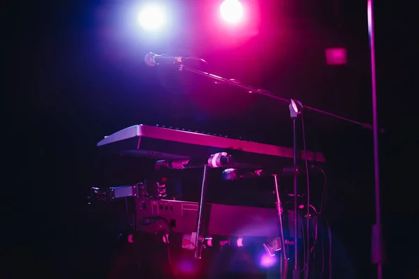 Keyboard synthesizer and vocal microphone on stage at rock and roll festival.Professional musical instrument on scene in night club.Play music on rock concert in concerts hall.Synth and mic on concert