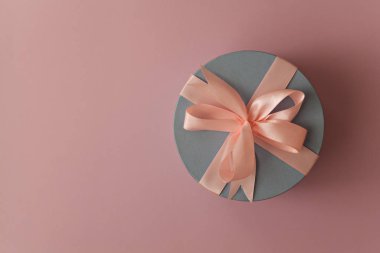 Pembe arka planda yuvarlak mavi hediye kutusu