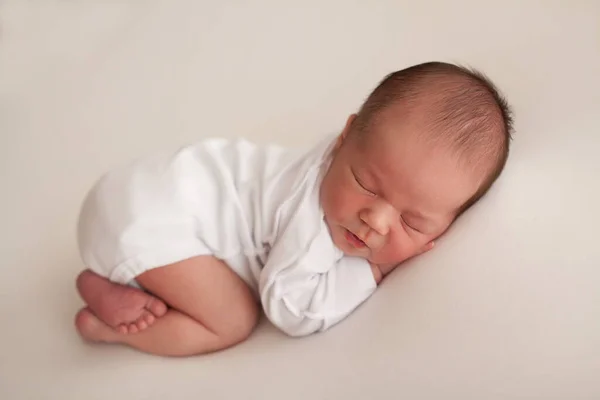 新生児の男の子は白い上で眠る ストック写真
