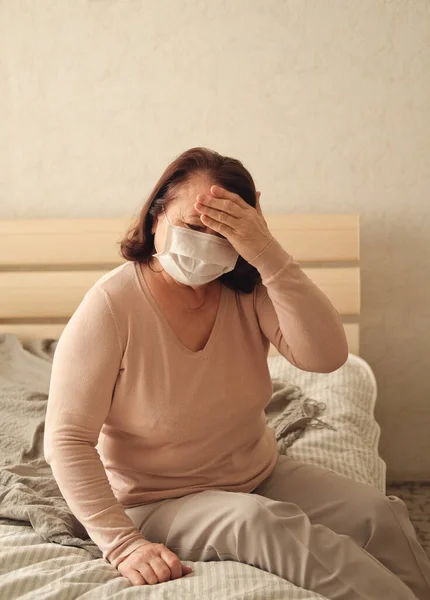 戴着护目镜的发烧老年妇女孤立无援地呆在家里 免版税图库照片