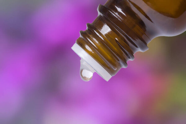 Macro shot of a bottle with drop on purple background