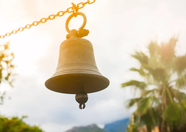 Bell opknoping op een keten met palmen op de achtergrond — Stockfoto