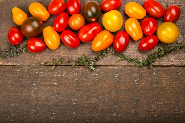 Tomates cherry coloridos maduros textura y tomillo en mesa de madera . — Foto de Stock