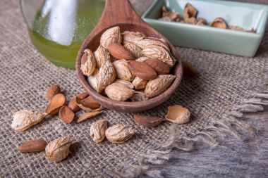 Kendi derileri ve ahşap arka plan üzerinde kahverengi kase peele badem.