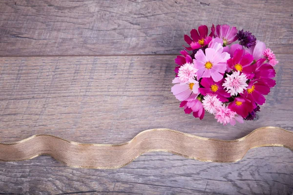 Un ramo de flores rosa y púrpura cosmética o cosmos con cinta en tablas de madera rústica. Copiar espacio. Madres, San Valentín, Mujeres, concepto del día de la boda — Foto de Stock