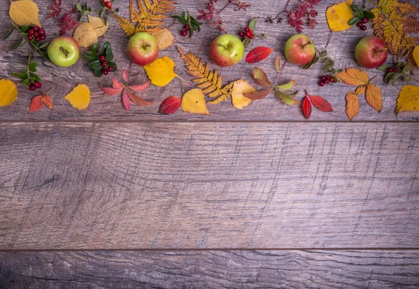 Arreglo otoñal de hojas, manzanas y bayas sobre un fondo de madera con espacio libre para texto. Vista superior, concepto de la temporada — Foto de Stock