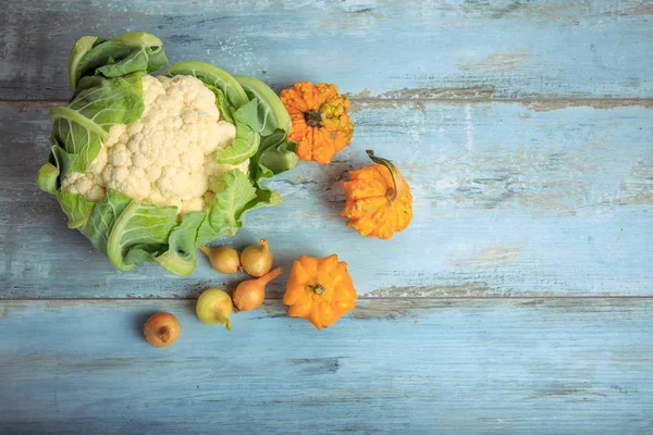 Zucca decorativa, cavolfiore e cipolle su uno sfondo di legno blu rustico. Note di alimentazione, concetto vegetariano . — Foto Stock