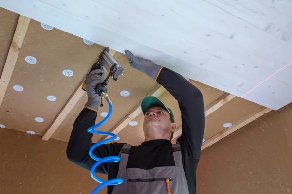 Construction worker thermally insulating eco wooden frame house — Stock Photo, Image