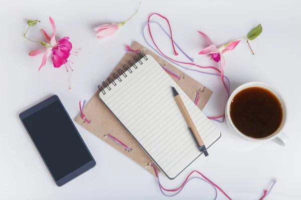 Creative flat lay photo of workspace desk with smartphone, coffee, pencil, flowers with copy space background. Flat lay