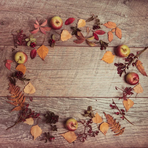 Arreglo otoñal de hojas, manzanas y bayas sobre un fondo de madera con espacio libre para texto. Vista superior, concepto de la temporada — Foto de Stock