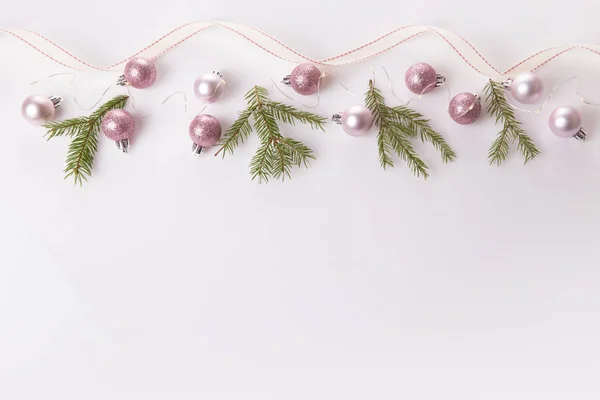 Composición navideña. Ramas de abeto, árbol de Navidad, bola de fiesta de decoración rosa de Navidad con cinta sobre fondo blanco. — Foto de Stock