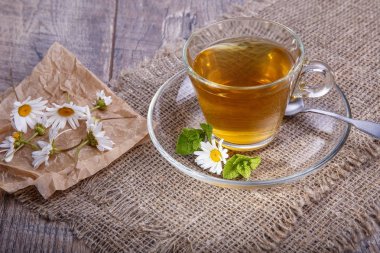 Bir fincan çay papatya ahşap arka plan ile. Alternatif ve geleneksel tıp