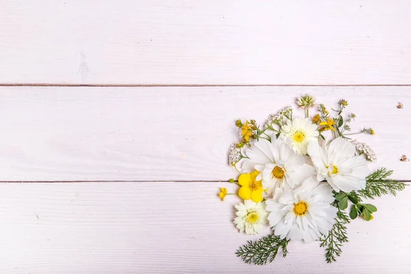 Kytice bílých květů cosmea nebo cosmos s mašlí na bílé tabule. Zahradní květiny žluté pozadí ručně vyrobený dřevěný stůl. Pozadí s kopií prostor. — Stock fotografie