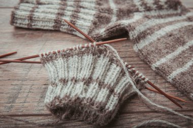 Dairesel bambu örgü iğneleri, gözlük, doğal renk yün iplik, ahşap rustik masa gözlük ile çorap örme işlemi.