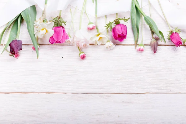 Ramillete de flores primaverales, tulipanes rosa, púrpura, narcisos y margaritas sobre fondo de madera blanca . — Foto de Stock