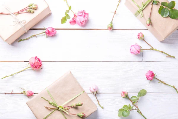 Composición de flores. Espacio de trabajo con flores de rosa, regalo, bolsa de papel. Vista superior, plano . — Foto de Stock