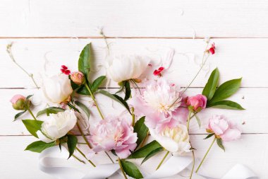Yaprakları çiçek ve ahşap tahta üzerinde beyaz kurdele ile hassas beyaz pembe Şakayık. Ek yükü üstten görünüm, düz yatıyordu. Uzay kopyalayın. Doğum günü, anne, Sevgililer, kadın, düğün günü kavramı