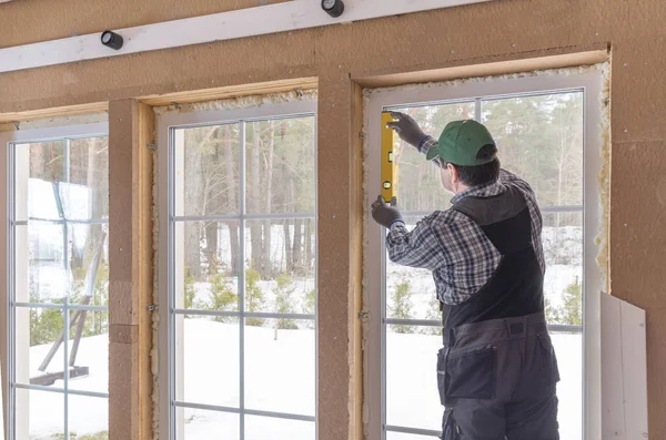 Construction worker thermally insulating eco wooden frame house with wood fiber plates. Latvia Stock Photo