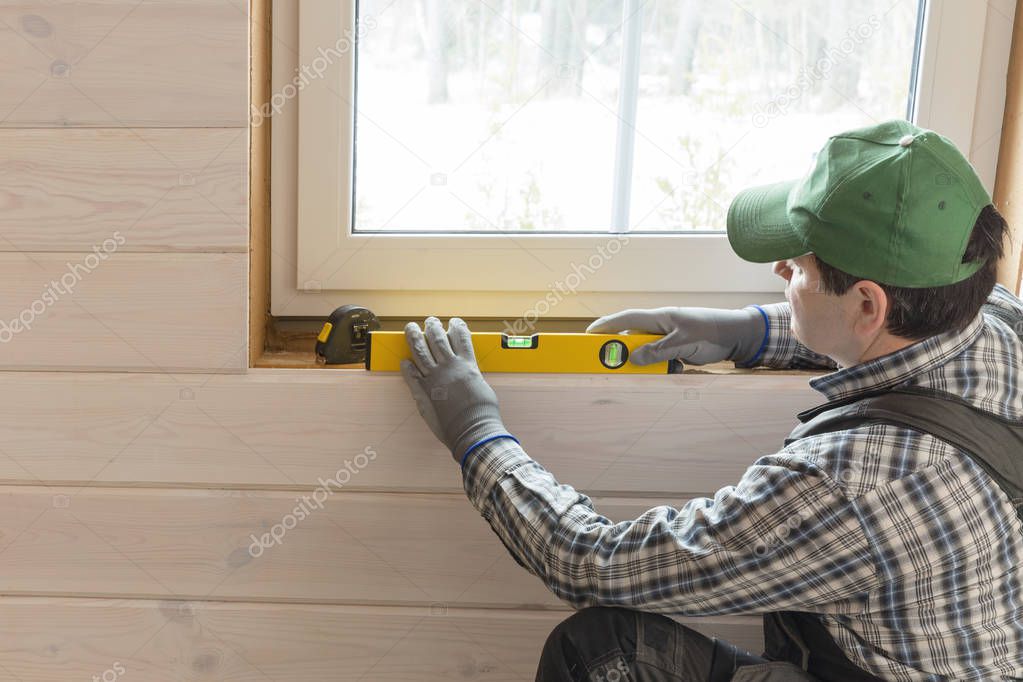 Construction worker thermally insulating eco wooden frame house with wood fiber plates. Latvia