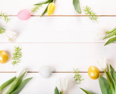 Paskalya yumurtaları ve bahar çiçekleriyle paskalya arkaplanı. Kopyalama alanı olan üst görünüm