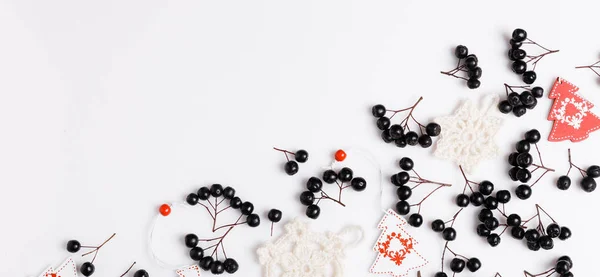 Composizione con bacche di chokeberry nero e decorazioni bianche e rosse, alberi di Natale e fiocchi di neve lavorati a maglia su sfondo bianco. Il concetto di Natale, inverno, Capodanno, cambio di stagione . — Foto Stock