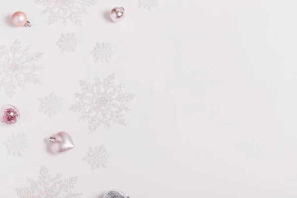 Composición navideña. Marco de bolas y copos de nieve sobre fondo gris pastel . — Foto de Stock