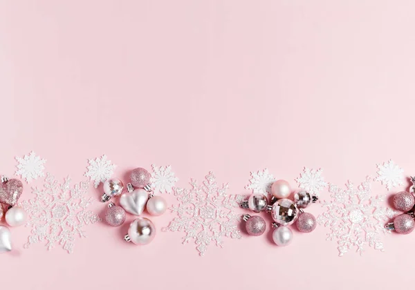 Composición navideña. Marco de bolas y copos de nieve sobre fondo rosa pastel . — Foto de Stock