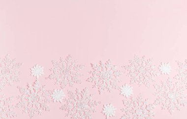 Noel kompozisyonu. Toplardan ve kar tanelerinden yapılmış çerçeve pembe arka planda.