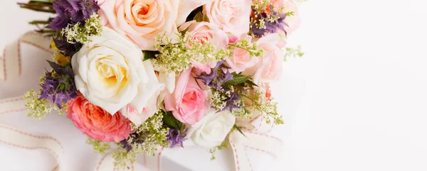 Zarter Strauß rosa Rosen Blumen und Geschenke mit Schleife auf dem Tisch. — Stockfoto