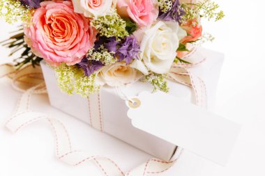 Zarif bir buket pembe gül çiçekleri ve masada kurdeleli hediyeler..