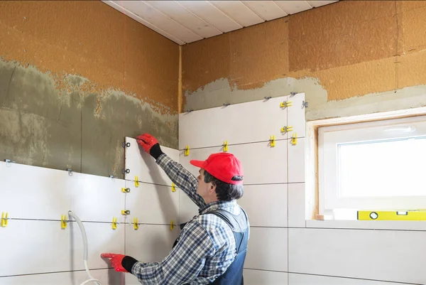 Ein Arbeiter verlegt Keramikfliesen und baut ein Haus — Stockfoto