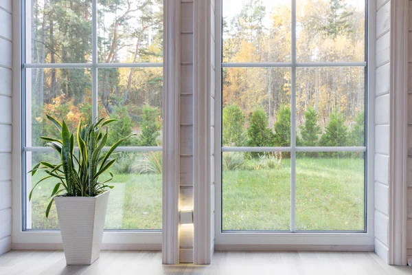 Büyük pencereli, yüksek tavanlı, beyaz ahşap zeminli parlak fotoğraf stüdyosu.