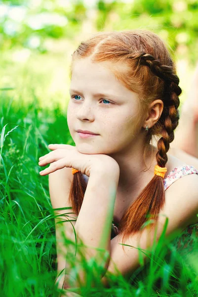 Belle rousse fille avec panier de fleurs dans l'herbe verte — Photo