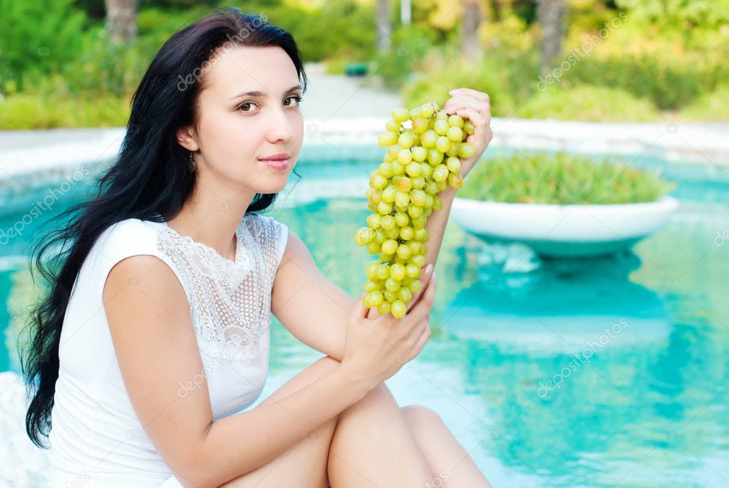 Beautiful young woman with green grapes. 