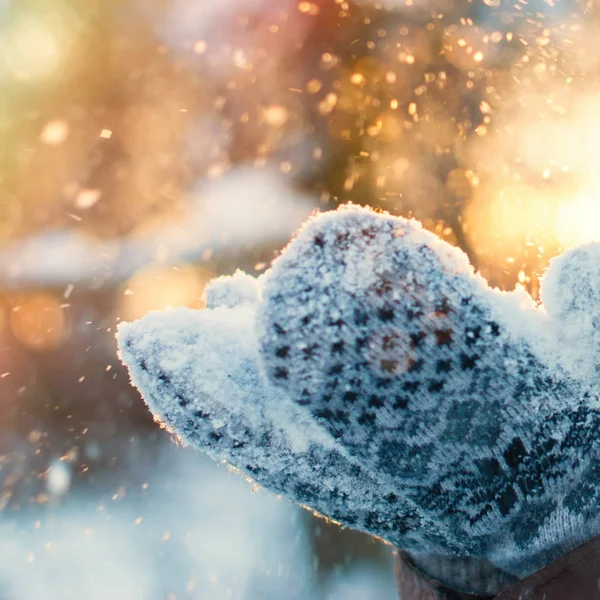 Winterhintergrund - Frauenhände in Handschuhen mit fliegenden Schneeflocken — Stockfoto