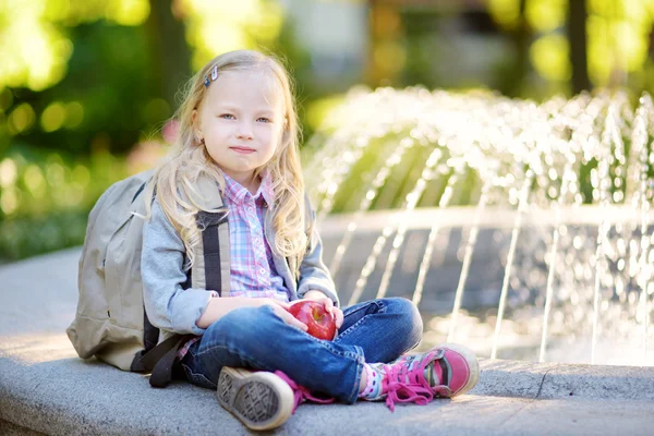 Adorable little schoolgirl in a city park — Stock fotografie