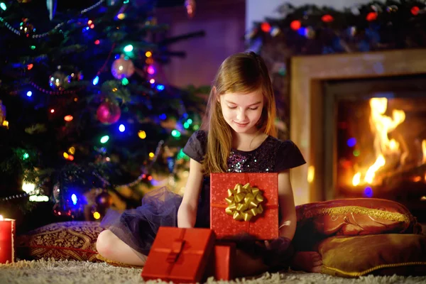 Dziewczyna, otwierając prezent przy kominku — Zdjęcie stockowe