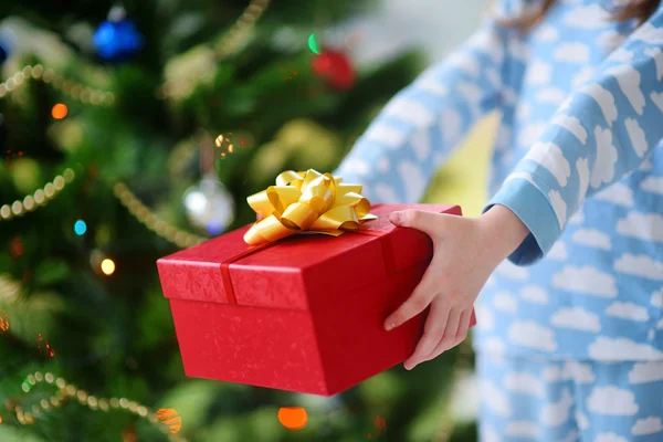 Enfant en pyjama tenant un cadeau de Noël — Photo