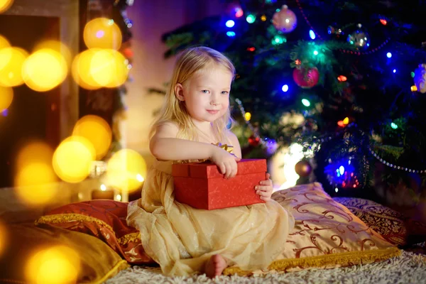 Девушка открывает рождественский подарок у камина — стоковое фото